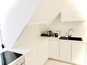 乌斯特卡Apartamenty VIP的白色的厨房配有白色橱柜和水槽