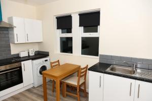 桑德兰AA Sunderland North的厨房配有白色橱柜、桌子和水槽。
