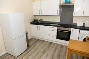 桑德兰AA Sunderland North的厨房配有白色橱柜和白色冰箱。