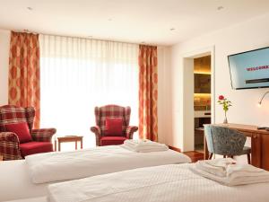 农嫩霍恩Hotel Hornstein - Weingut, Vinothek & Gastronomie的酒店客房,配有两张床和两把椅子