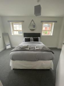 麦斯堡Doncaster Furnished House For Short Lets的白色客房内的一张大床,设有两个窗户