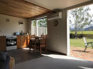 布伦海姆Vineyard Cottage in Blenheim on the Golden Mile的厨房以及带桌子和窗户的用餐室。