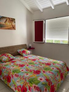 Les GaletsPARADIS DES SABLES的一间卧室配有一张带花卉床罩的大床