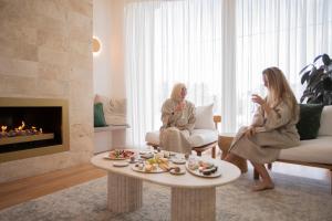 安吉西大洋路度假酒店的两名女性坐在客厅里,配有咖啡桌