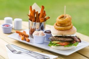 朗塞斯顿Trethorne Hotel & Golf Club的带有汉堡包的盘子,带有洋葱环和薯条