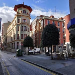 希洪Hostel GoodHouse Gijón的一条城市街道,街道上有许多建筑和桌子,树木