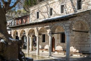 马克里尼撒Philos Guesthouse的庭院中一座带拱门的古老石头建筑