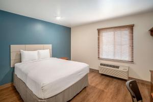 科珀斯克里斯蒂WoodSpring Suites Corpus Christi的卧室配有白色的床和窗户。