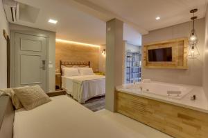 弗洛里亚诺波利斯Solar Beach Hotel的一间带浴缸、床和电视的卧室