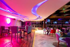 莫雷利亚HOTEL & SPA MANSION SOLIS by HOTSSON的用餐室配有粉红色的灯光和桌椅