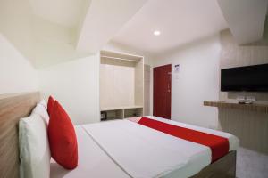 马尼拉OYO 675 Circuit Hostel的一间卧室配有一张带红色枕头的床和一台电视。