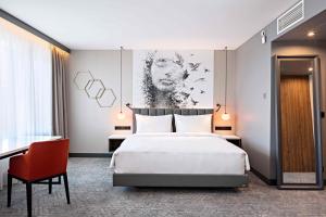 里加里加道加瓦丽笙布鲁酒店的卧室配有一张白色大床和红色椅子