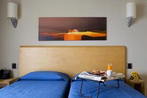 陶尔米纳Taormina Panoramic Hotel的一间卧室配有一张蓝色的床,上面有桌子