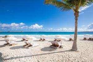 东方湾埃斯梅拉达度假村的海滩上摆放着椅子和遮阳伞,还有棕榈树
