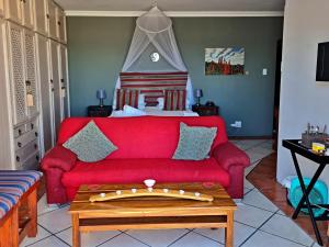 干斯拜Walkerbay Accommodation的客厅配有红色的沙发和床。