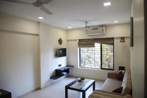 孟买Lite Stays - Vile Parle East的带沙发、桌子和窗户的客厅