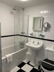 坎特伯雷Canterbury Hotel Cottages and Apartment's的白色的浴室设有水槽和淋浴。