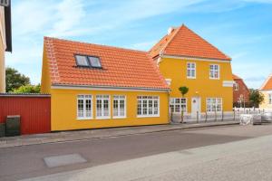 斯卡恩1 Skøn og lyst indrettet feriehus i Skagen的街上一座黄色房子,屋顶橙色