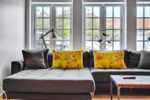 斯卡恩1 Skøn og lyst indrettet feriehus i Skagen的客厅配有带黄色枕头的灰色沙发