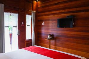 龙目岛库塔La'villaris hotel & resto的一间卧室设有木墙,配有电视