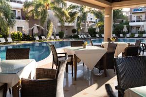 加藤-达拉特索Okeanis Golden Resort的游泳池旁的餐厅配有桌椅