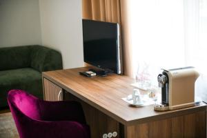 巴尼亚卢卡Hotel Zepter Palace的配有电视和桌椅的房间