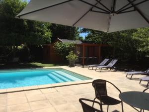 Charrey-sur-Saônela Grange de Félicie的一个带椅子和桌子的游泳池以及一把遮阳伞
