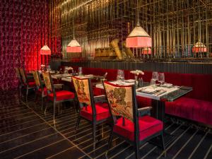 河内Capella Hanoi的一间配备有桌椅和红色窗帘的用餐室