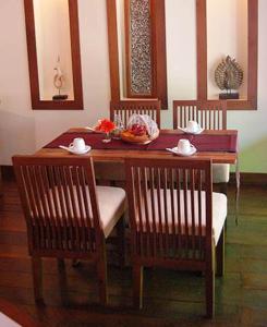 清迈考本金吧别墅酒店的一张木桌,配有两把椅子和一张桌子及碗