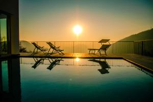 萨罗Il Bagnolo Eco Lodge的一个带椅子的游泳池,享有日落美景