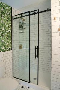 圣凯瑟琳市The Juniper Inn的浴室设有玻璃淋浴间,铺有白色瓷砖
