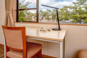 奈良奈良县游客交流馆 & 住宿中心的一张带台灯和椅子的桌子以及一扇窗户
