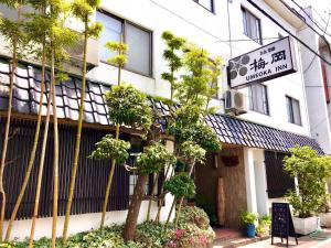 长野梅岡日式旅馆的一座有树木和前面标志的建筑