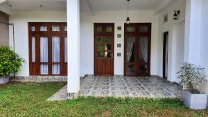 阿努拉德普勒Elite Holiday Home, Anuradhapura的两扇门和草地庭院的房子