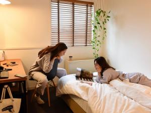 金泽金泽太平洋酒店的两个女孩坐在房间里的床边