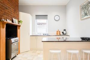 吉朗Quartz Cottage Geelong的厨房设有白色的墙壁和带凳子的台面