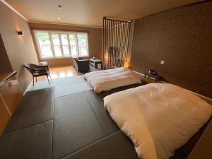 富士河口湖Auberge Mermaid的一间卧室配有两张床、一张桌子和一把椅子