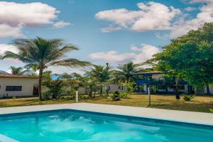 塞古罗港Pousada Migo的棕榈树屋前的游泳池