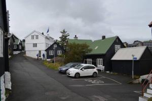 托尔斯港Cosy house in the heart of Tórshavn (Á Reyni)的两辆汽车停在房子旁边的停车场