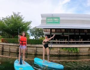 北碧Good Times Resort Kanchanaburi的两个女孩站在水中的桨板上