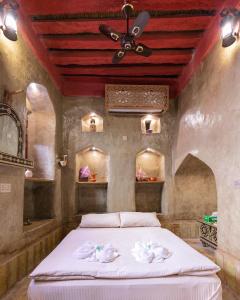 尼兹瓦Bait Al Aqr的一间卧室配有一张带白色床单和天花板的床。