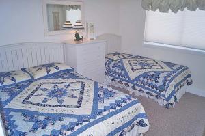 大洋城Capri 1908的一间卧室配有两张带蓝色和白色棉被的床。