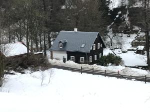 MařeniceChalupa Rozmarýna的雪中带栅栏的黑色房子