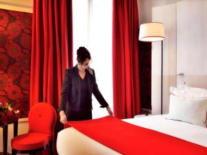 里昂Hotel Carlton Lyon - MGallery Hotel Collection的一位站在床边的女士,她用红毯