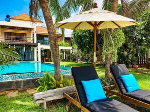 盼武里Baan SanSuk Pranburi - Beach Front & Pool Villa的游泳池旁的遮阳伞下的两把椅子