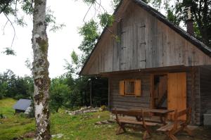 博希尼Gorska hiška Vogar nad Bohinjskim jezerom的小木屋前面设有长凳