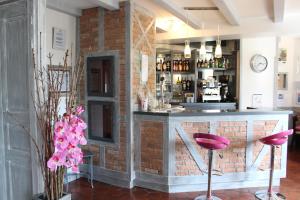 维特拉克Auberge La Tomette, The Originals Relais的砖墙前有粉红色凳的酒吧