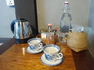 白马市高棉汉斯酒店的木桌边的两杯咖啡和一瓶