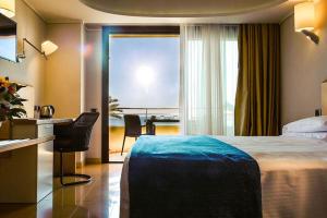 陶尔米纳Taormina Panoramic Hotel的配有一张床、一张书桌和一扇窗户的酒店客房