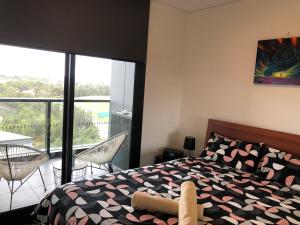 悉尼Parkview Modern Apartment w Parking @ Olympic Park的一间卧室设有一张床和一个阳台